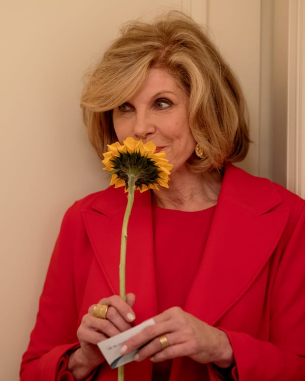   Christine Baranski nei panni di Diane Lockhart che odora un girasole e indossa un abito rosso brillante"The Good Fight" Season 6 on Paramount Plus