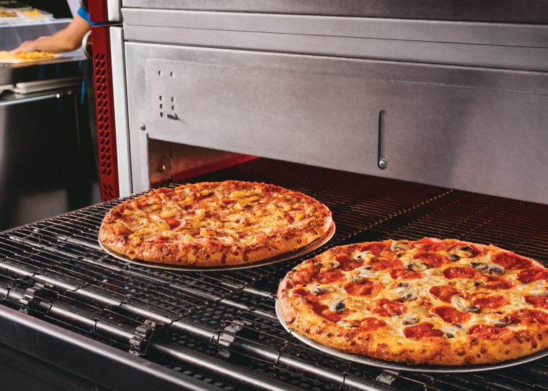  Тво Домино's pizzas going into the oven