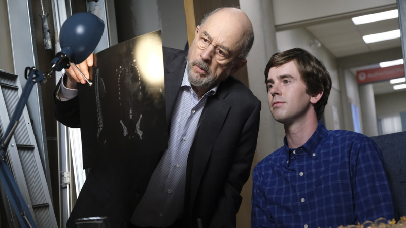   Richardas Schiffas, kaip daktaras Aaronas Glassmanas, dešine ranka laiko rentgeno nuotrauką prieš stalinę lempą ir dalijasi juo su Freddie Highmore'u, kaip daktarą Shauną Murphy, ABC serijoje „Geras gydytojas“